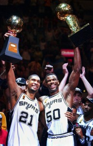 San Antonio Spurs players Tim Duncan (21) holds his MVP trophy while teammate David Robinson (50) holds the championship trophy after the Spurs beat the New Jersey Nets 88-77 to win the NBA Championship in Game 6 of the NBA Finals in San Antonio, June 15, 2003. The sports year in Texas got off to a rousing start with Bill Parcells saying on Jan. 1 that he had agreed to coach the Dallas Cowboys and soon after, the San Antonio Spurs gave David Robinson the ultimate reitrement present, an NBA title. (AP Photo/Eric Gay, file)
